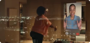 Persona utilitzant les Apple Vision Pro per fer una videotrucada immersiva en un entorn domèstic amb vistes nocturnes.